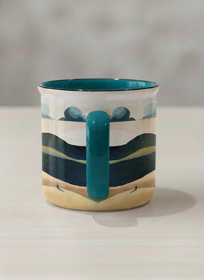 enamel mug | Share a Sunset side view  mug a lone figure walking through rolling sand dunes beneath a glowing orange sun and layered teal clouds, deep teal interior and handle, by KikaG - Gallery By Inhesion