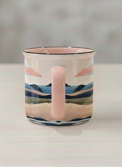 enamel mug | Sunset at the River side view mug rolling hills and dark treetops beneath a soft peach sky with blush and teal clouds and a glowing setting sun, warm peach interior and handle, by KikaG - Gallery By Inhesion