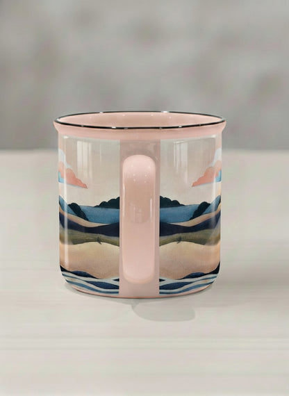 Enamel mug | Sunset at the River side view mug rolling hills and dark treetops beneath a soft peach sky with blush and teal clouds and a glowing setting sun, warm peach interior and handle, by KikaG - Gallery By Inhesion