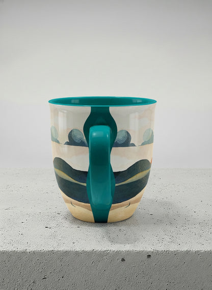 ronny mug | Share a Sunset side view  mug a lone figure walking through rolling sand dunes beneath a glowing orange sun and layered teal clouds, deep teal interior and handle, by KikaG - Gallery By Inhesion
