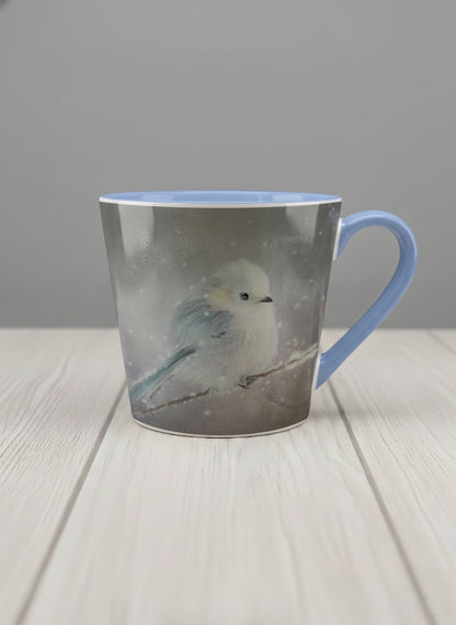conical mug | A Moment in the Snow mug, a fluffy white bird perched quietly in a soft wintry haze, sky blue interior and handle, by Karina Mosser - Gallery By Inhesion